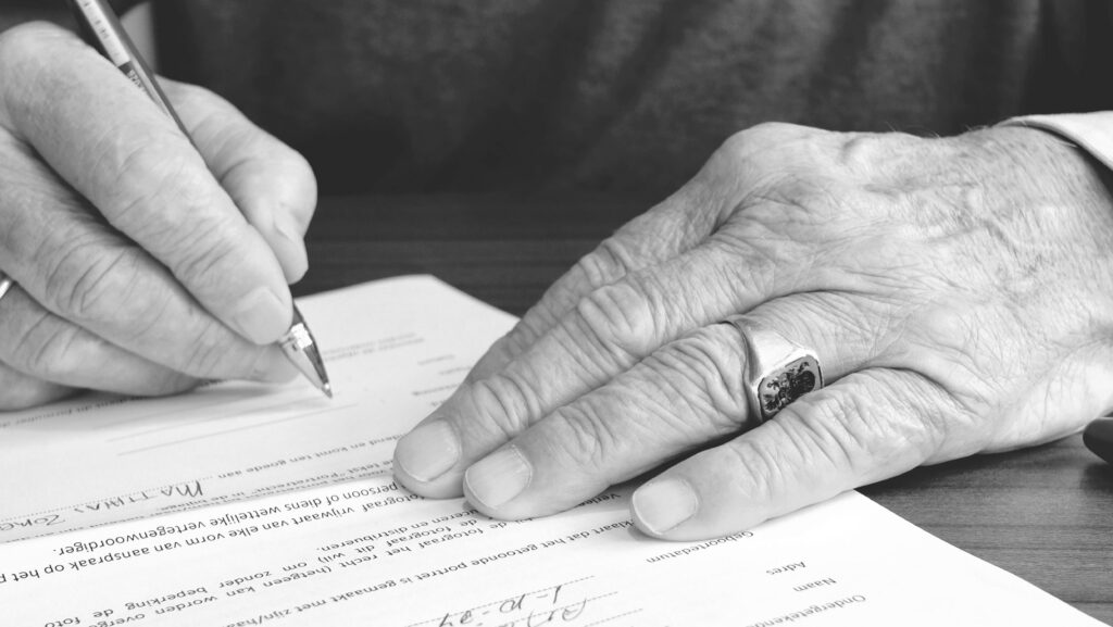 Ręka pisząca testament na papierze – prawo spadkowe i pomoc, jaką oferuje adwokat w Szczecinku
