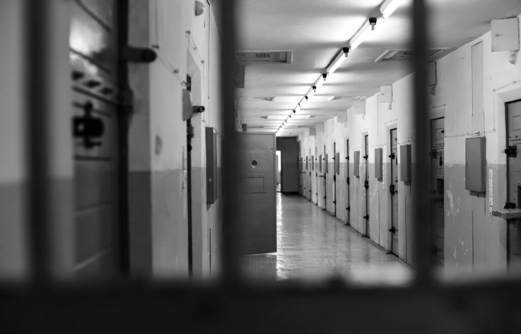 Widok zza więziennej kraty widać przez nie resztę korytarzy więziennych, przed więzieniem może uchronić pomoc adwokata ze Szczecinka