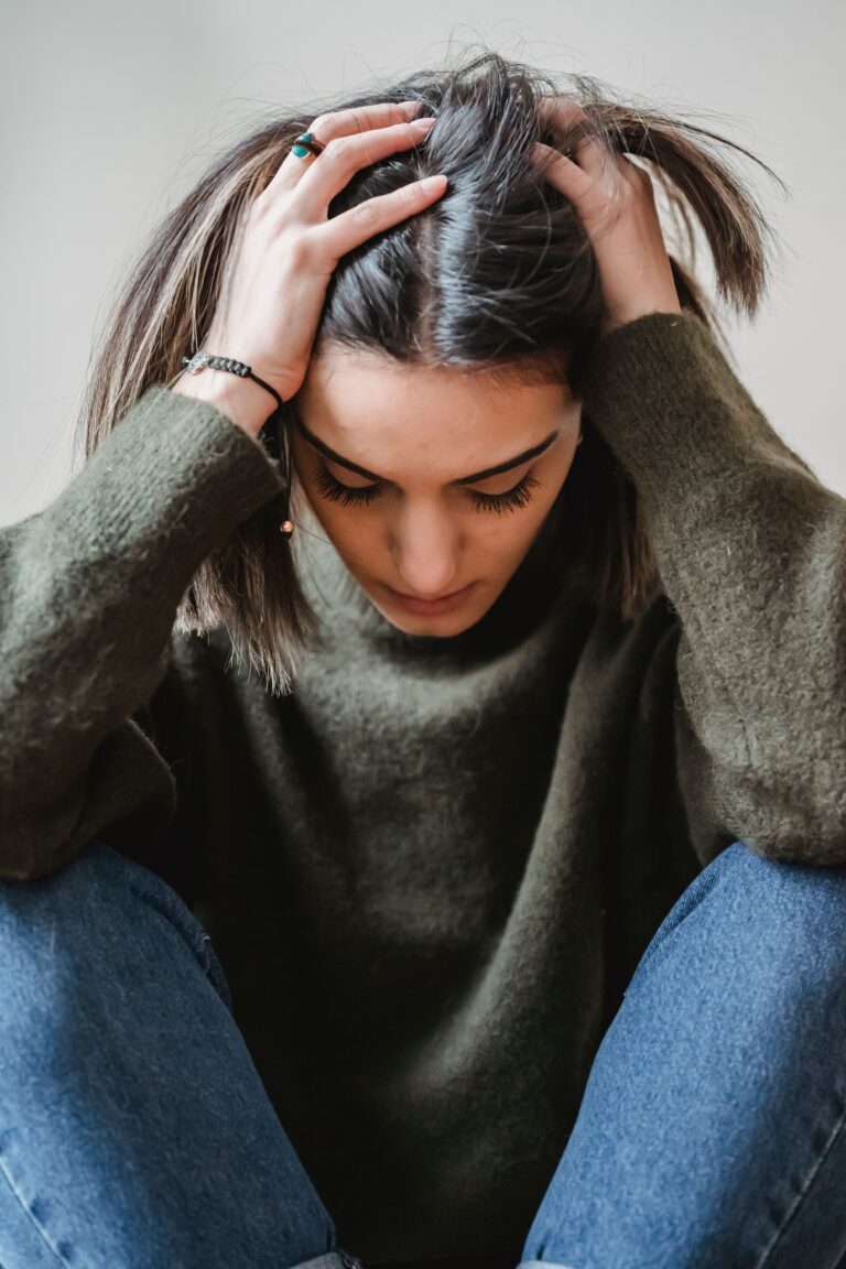 Kobieta załamana psychicznie trzyma się za głowę, trzeba ją skierować na leczenie psychiatryczne w którym pomoże adwokat w Szczecinku